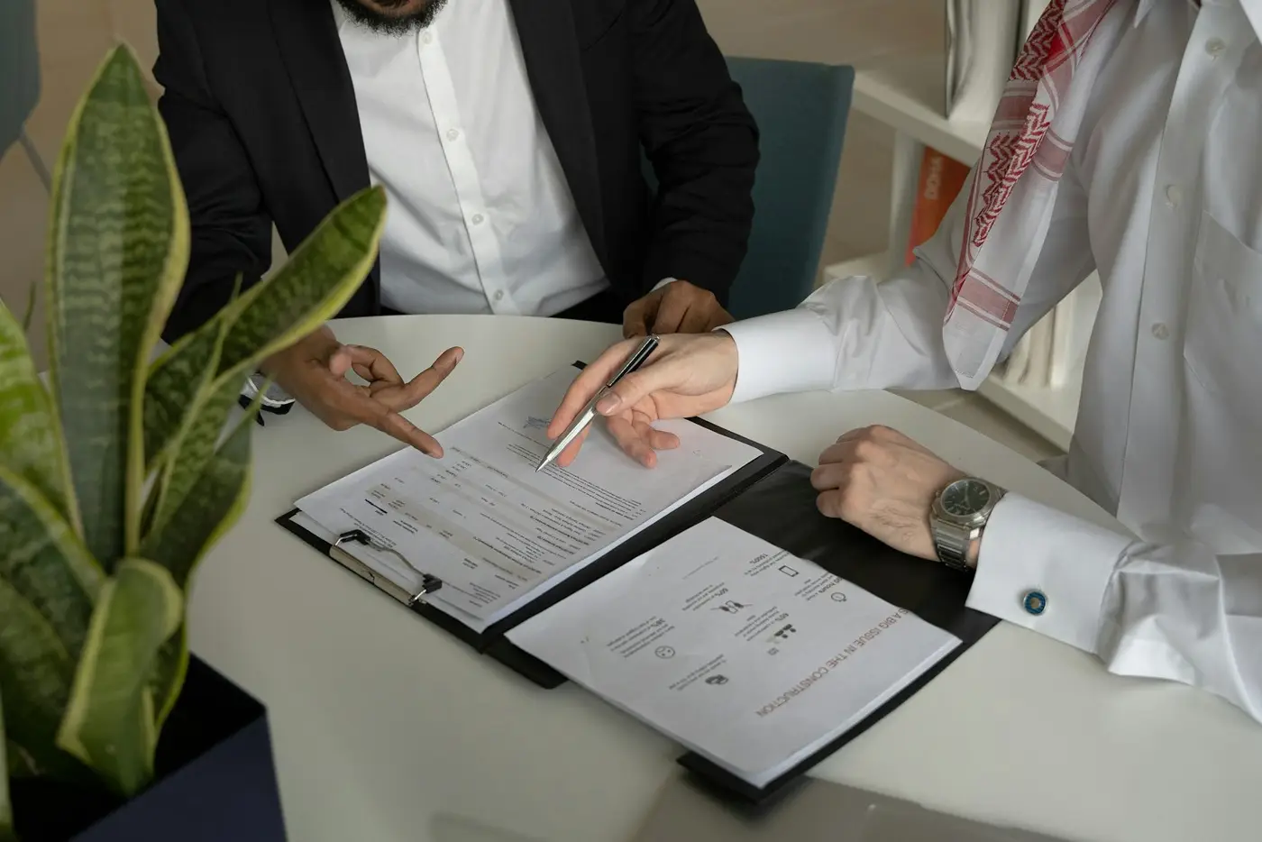 Zwei Männer am Tisch mit Papieren und Stift